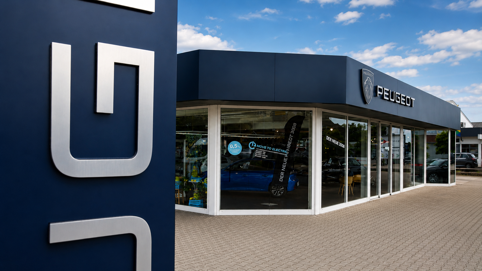 Peugeot-Autohaus mit modernem Showroom und blaues Logo auf der Fassade an sonnigem Tag.